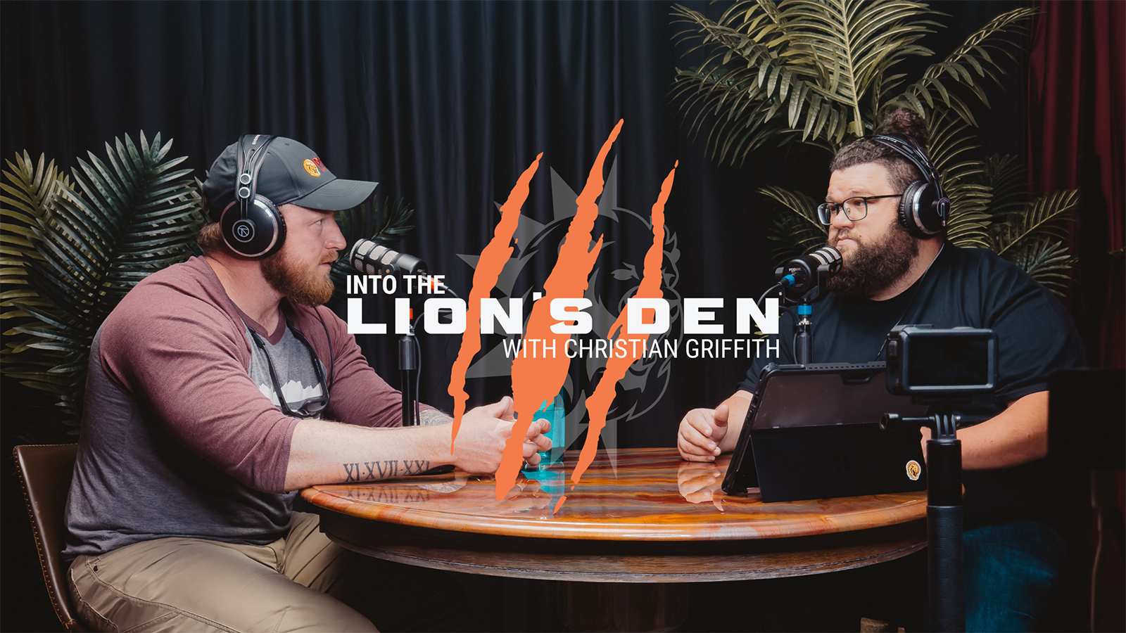 Original Into the Lion’s Den studio artwork, with two people in conversation at microphones